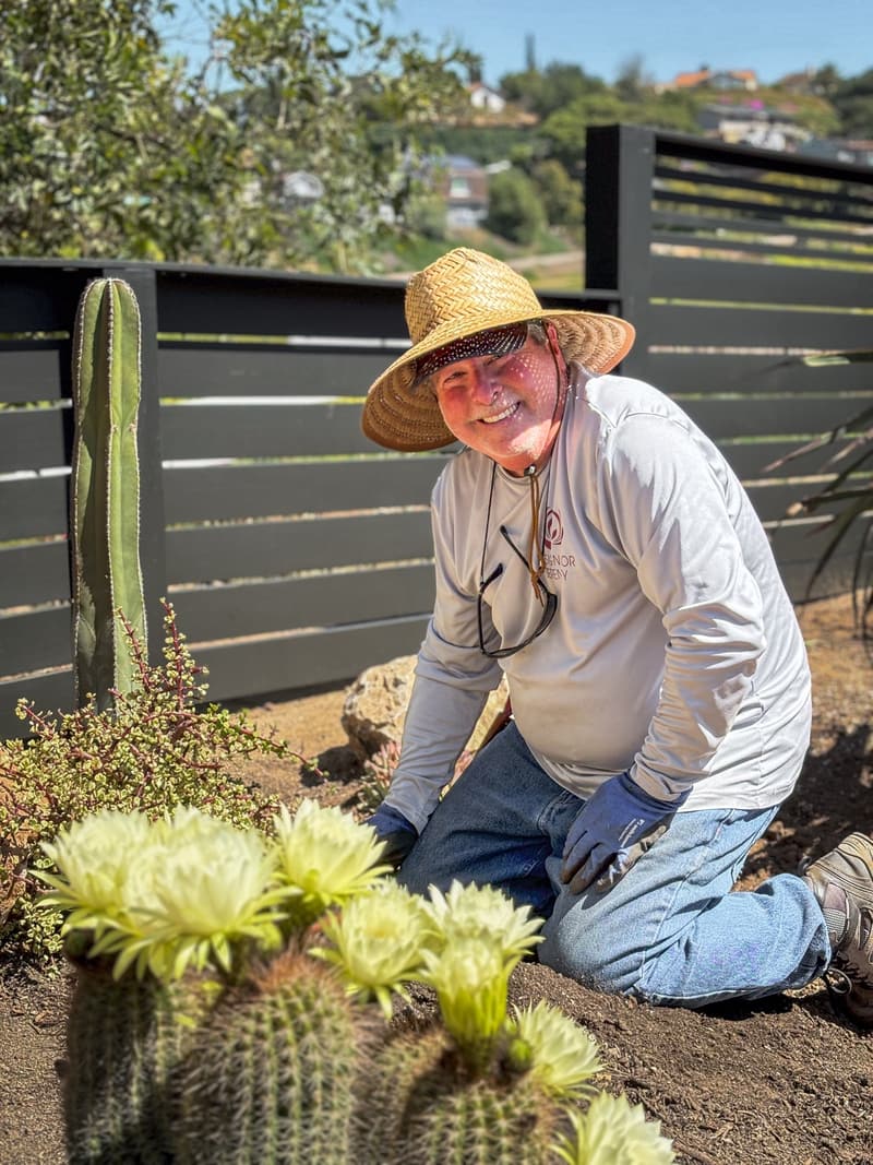 A Design for Serenity crew member kneeling beside cacti in full bloom